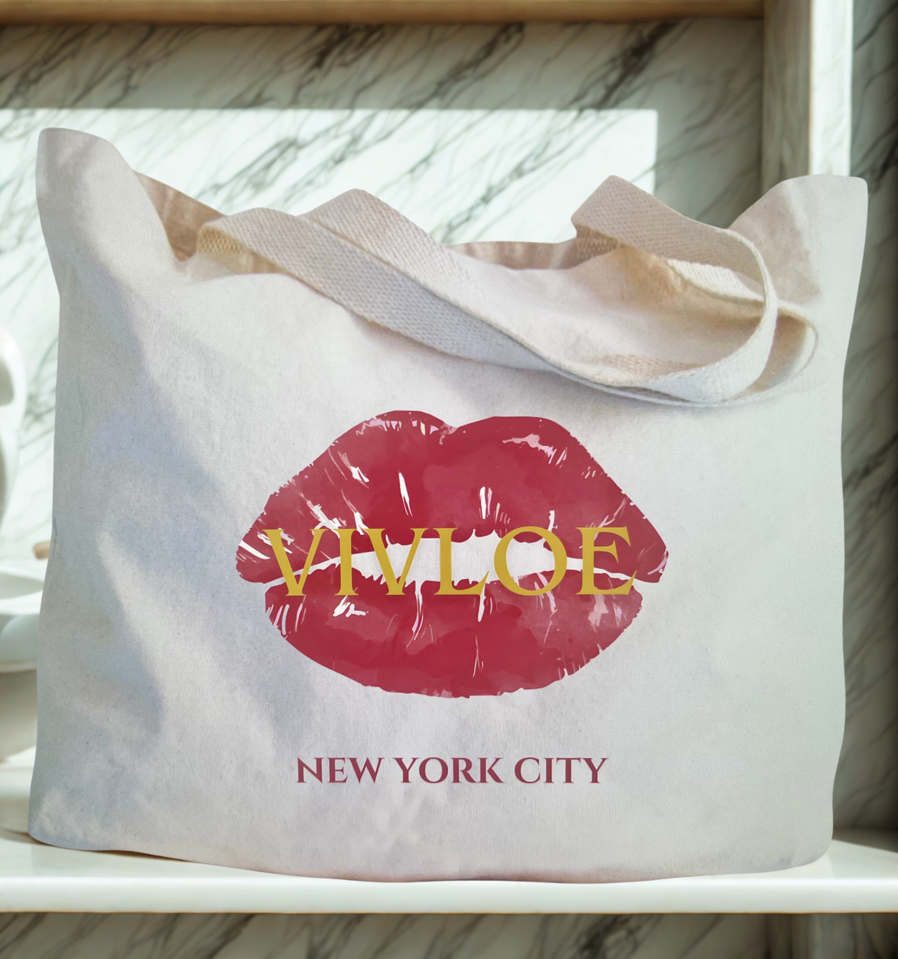 Tote bag with red lips and 'Vivloe New York City' text on a marble surface
